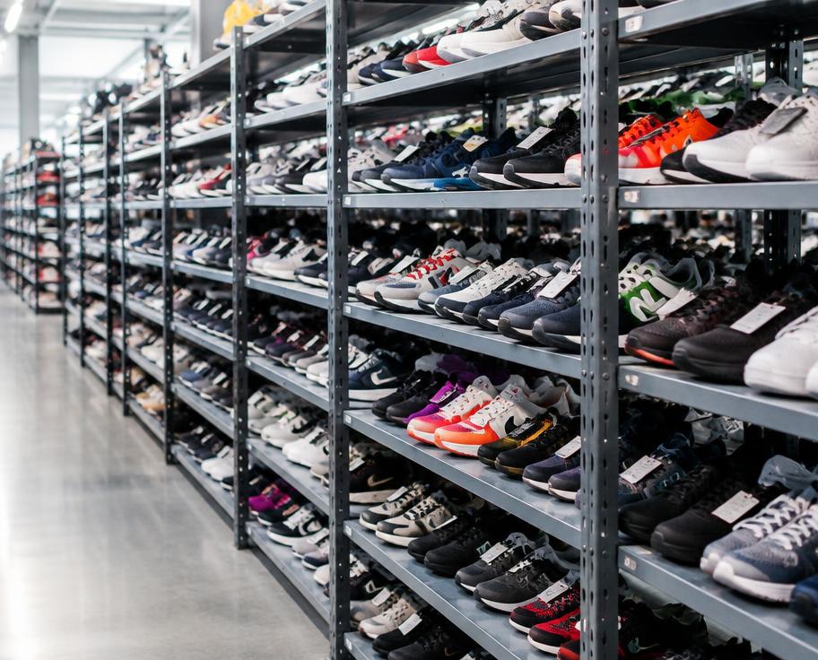 Rows of clean second-hand trainers and shoes on warehouse shelving